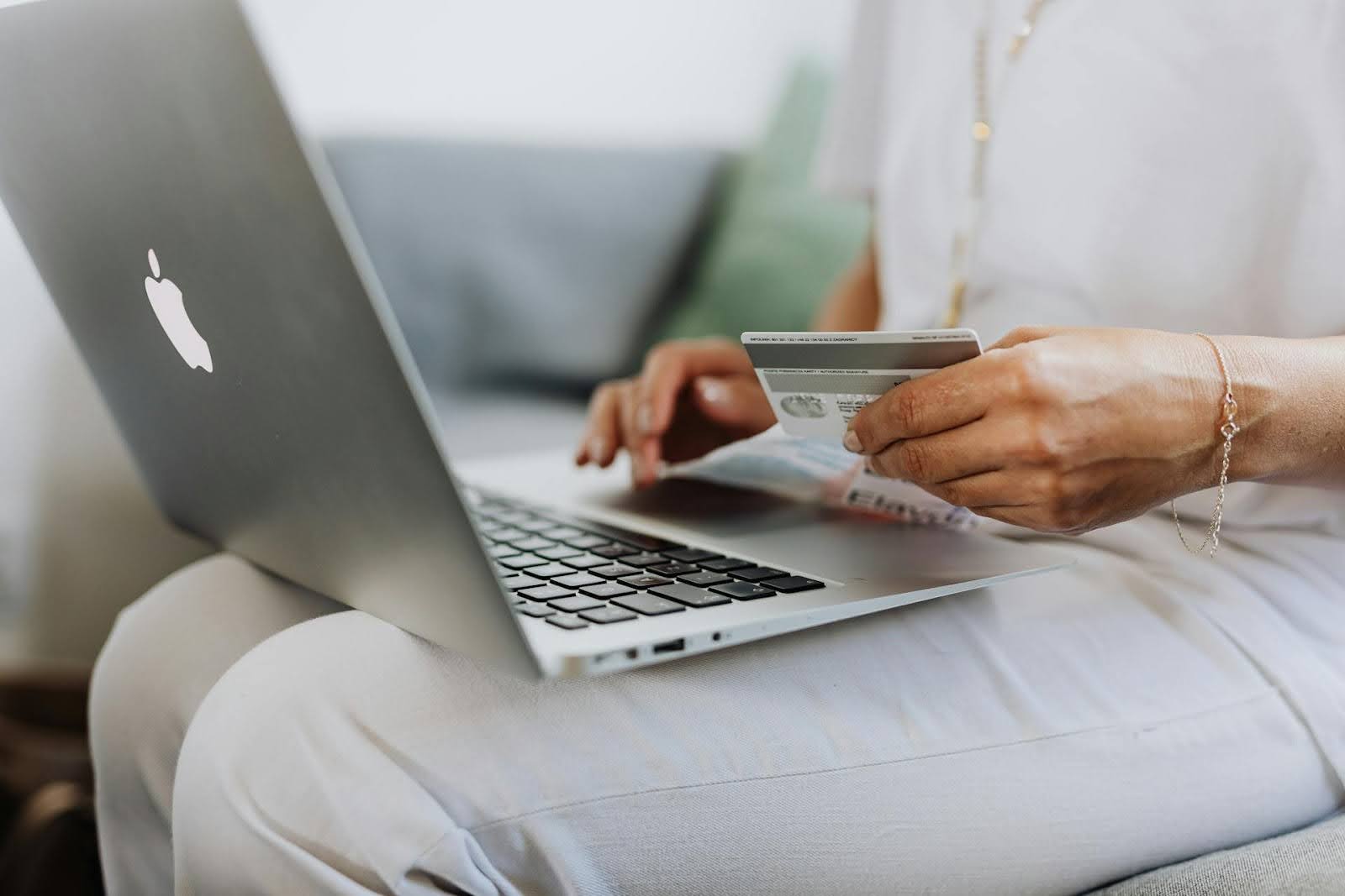 a woman using a laptop while holding her credit card