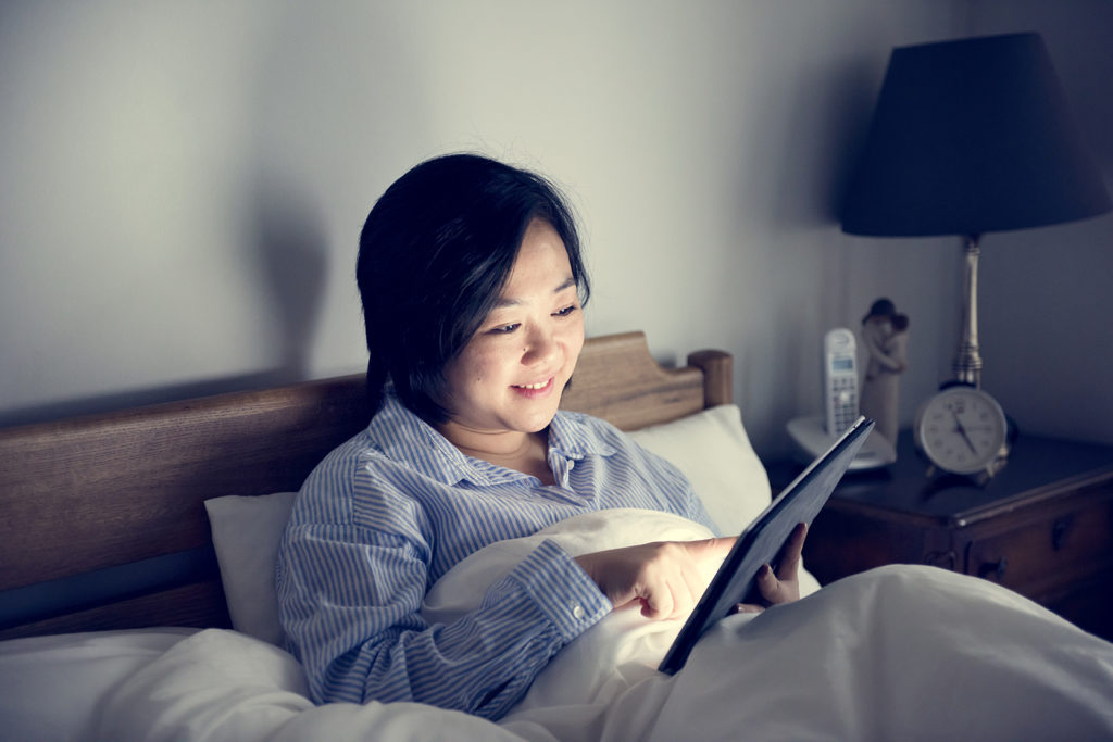 A woman using a tablet in bed