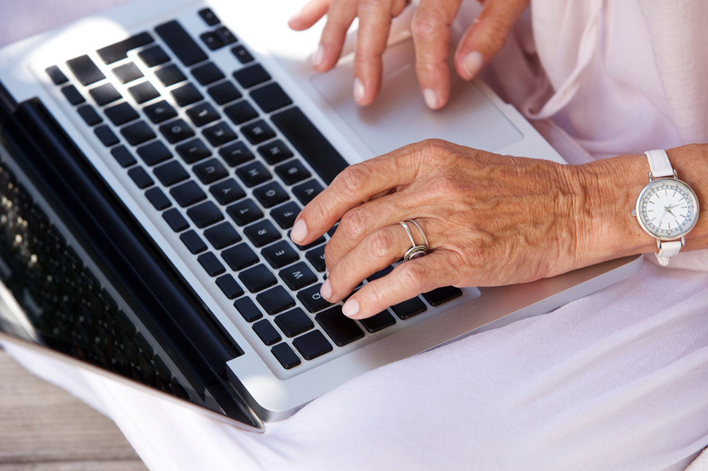 older woman typing on laptop computer