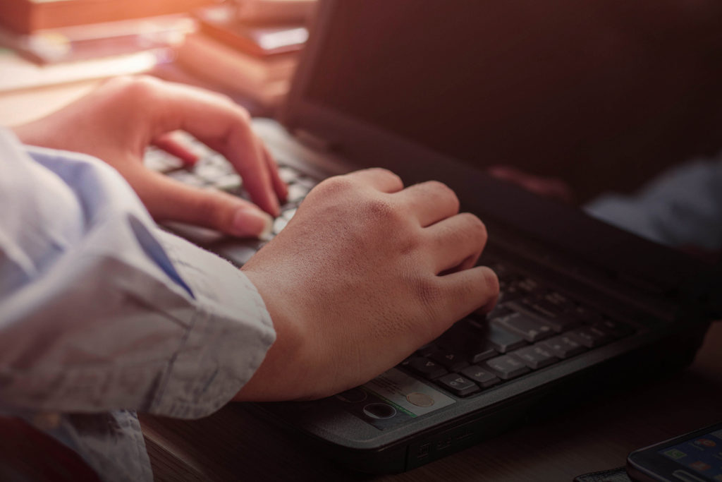 Hands typing on a notebook