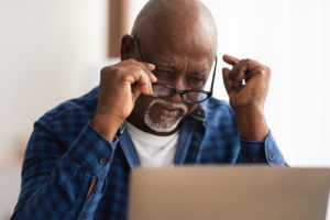 Senior Black Man Squinting Eyes Taking Off Eyeglasses Indoor