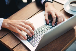 Close-up man hands with accurate manicure, typing on laptop